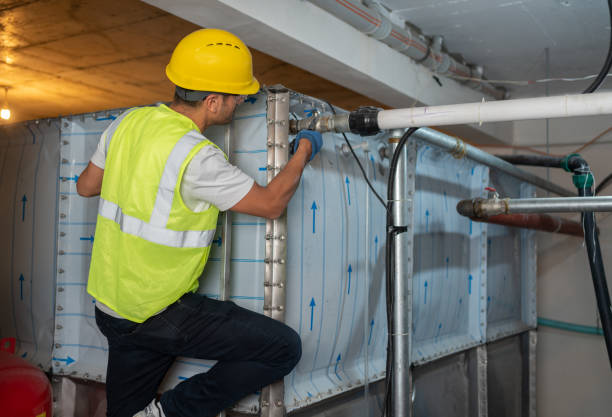 A Prime Plumbing Services technician in safety gear working on a basement water system, representing the best basement plumbing contractors Edmonton.